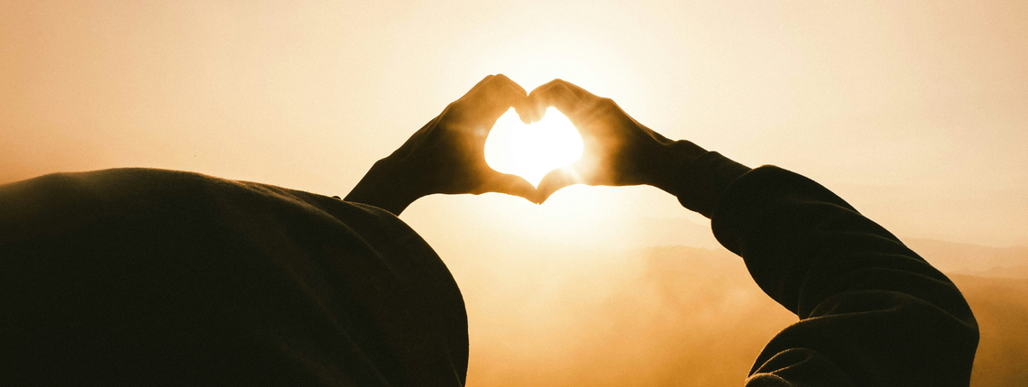 hands making a heart in the sun
