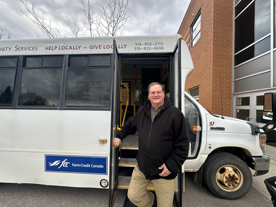 smiling man standing outside of white bus